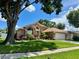 Well-maintained property featuring green lawn, lush landscaping, and an attached two-car garage at 28826 Windover St, Wesley Chapel, FL 33545