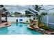 A serene screened-in pool with rock waterfall feature, lush greenery, and view of the home's outdoor amenities at 28826 Windover St, Wesley Chapel, FL 33545