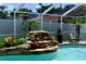 Screened-in pool featuring a rock waterfall with tropical landscaping at 28826 Windover St, Wesley Chapel, FL 33545
