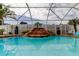 Backyard pool featuring a rock waterfall, tropical plants, and a screened enclosure at 28826 Windover St, Wesley Chapel, FL 33545