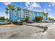 Low angle shot of blue condominium building with a parking lot full of cars, blue skies and palm trees at 3315 58Th S Ave # 311, St Petersburg, FL 33712