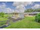 Image of a barn on a grassy property with an open gate and other structures in the background at 3505 Medulla Rd, Plant City, FL 33566