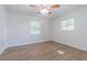 This bright bedroom offers hardwood floors, a ceiling fan, and natural light through two windows with lawn views at 3505 Medulla Rd, Plant City, FL 33566