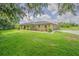 This property features a large front yard, brick facade, metal roof, and mature landscaping at 3505 Medulla Rd, Plant City, FL 33566