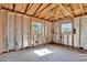 Partially renovated room featuring exposed wood framing, insulation and large windows at 4173 85Th N St, St Petersburg, FL 33709