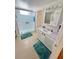 Well-lit bathroom with a step-in shower, teal rugs, and vanity with updated fixtures, combining style and functionality at 4851 W Gandy Blvd # B7L36, Tampa, FL 33611