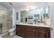 Bathroom features double sink vanity with dark wood cabinets, large mirror, and glass enclosed shower at 5410 River Sound Ter, Bradenton, FL 34208