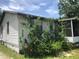Side view of the home with overgrown landscaping at 6403 Elliot Dr, Tampa, FL 33615