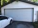 Exterior shot of a detached garage with a white door and a white vehicle parked nearby at 6403 Elliot Dr, Tampa, FL 33615