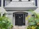 Charming front entrance with a black door, decorative wreath, and lush tropical landscaping at 6925-A Avenue Des Palais # 1A, South Pasadena, FL 33707