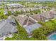Aerial view of a home with a screened lanai and pool, surrounded by lush landscaping and a well-maintained neighborhood at 7114 Bowspirit Pl, Apollo Beach, FL 33572