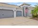 Home featuring a three car garage, American flag, and tropical landscaping at 7114 Bowspirit Pl, Apollo Beach, FL 33572