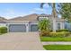 Well-maintained house with a three-car garage, mature trees, and manicured landscaping at 7114 Bowspirit Pl, Apollo Beach, FL 33572