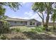 Backyard view of a charming home, surrounded by mature trees and a partially fenced yard at 7625 Marechal Ave, Port Richey, FL 34668