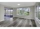 Dining area featuring a large window, gray wood floors, and a sliding glass door to a screened-in patio at 7625 Marechal Ave, Port Richey, FL 34668