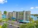 Beautiful condo building featuring waterfront views, covered parking, and tropical landscaping at 7892 Sailboat Key S Blvd # 408, South Pasadena, FL 33707