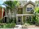 Inviting green home featuring a charming front entryway with lush, tropical landscaping at 945 Hamilton Ct, Palm Harbor, FL 34683