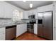 Well-lit kitchen featuring stainless steel appliances, white cabinetry, and beautiful terra cotta tile flooring at 945 Hamilton Ct, Palm Harbor, FL 34683