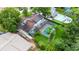 Aerial view of property featuring a pool, screen enclosure, solar panels, and a putting green at 10053 W Bay St, Seminole, FL 33776