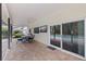 Covered brick patio featuring a ceiling fan, dining table, TV, and pool access through sliding glass doors at 10053 W Bay St, Seminole, FL 33776