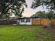 Fenced backyard with a mix of grass, trees, back patio, and wooden fence at 104 W Wildwood St, Tampa, FL 33613