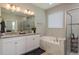 Bright bathroom with double vanity, soaking tub, and glass-enclosed shower at 12451 Nouveau Ave, Spring Hill, FL 34610