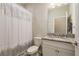 Well-lit bathroom with granite vanity and shower with a decorative curtain at 12451 Nouveau Ave, Spring Hill, FL 34610