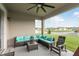 Covered patio featuring a wicker seating area with plush cushions, ceiling fan, and views of the fenced backyard at 12451 Nouveau Ave, Spring Hill, FL 34610