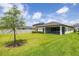 Spacious backyard with lush green grass, a young tree, and a screen enclosed patio for outdoor living at 12652 Shetland Walk Dr, Lithia, FL 33547