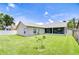 Wide view of the backyard with healthy green grass, a small tree, and enclosed patio area at 13602 Fawn Ridge Blvd, Tampa, FL 33626