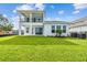 Rear view of a home showcasing a spacious lawn and a covered patio and balcony at 1583 Running Tide Pl, Sarasota, FL 34240