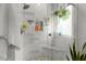 Modern bathroom featuring a tiled shower with a glass door, bench, and a window with hanging plants at 1631 Shady Oaks Dr, Oldsmar, FL 34677