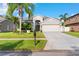 Charming one-story home with a well-manicured lawn, mature palm trees, and a two-car garage at 1631 Shady Oaks Dr, Oldsmar, FL 34677