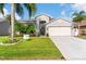 Well-maintained home with a lush green lawn, mature palm trees, and a clean, paved driveway at 1631 Shady Oaks Dr, Oldsmar, FL 34677