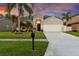 Inviting single-story home featuring a lush lawn, tropical landscaping, a two-car garage, and a paved walkway at 1631 Shady Oaks Dr, Oldsmar, FL 34677