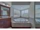 This bathroom features a soaking tub by bay window with plantation shutters, undermount sinks, and wood cabinets at 1830 Springwood N Cir, Clearwater, FL 33763