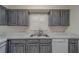 A close up of a the sink area of a kitchen with marble countertops and neutral toned cabinetry at 1830 Springwood N Cir, Clearwater, FL 33763