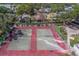 Aerial view of community tennis and basketball courts surrounded by trees and homes at 1830 Springwood N Cir, Clearwater, FL 33763