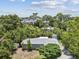 An aerial view showcasing the home with mature trees, lush landscaping, and a driveway at 1843 Berg Rd, Holiday, FL 34690
