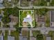 A bird's eye view of the property, surrounded by mature trees, and adjacent to a quiet street at 1843 Berg Rd, Holiday, FL 34690