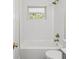 Bright bathroom featuring a white tiled shower, gold hardware, and natural light at 1843 Berg Rd, Holiday, FL 34690