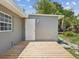Exterior view of home with grey stucco, white trim, wood deck and manicured landscaping at 1843 Berg Rd, Holiday, FL 34690