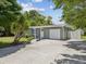 Single-story home featuring neutral grey paint, palm tree, and manicured landscaping at 1843 Berg Rd, Holiday, FL 34690