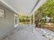 Covered patio with concrete floor is surrounded by mature trees and a glimpse of a shed at 1843 Berg Rd, Holiday, FL 34690