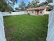 Backyard with a well-maintained lawn, bordered by a white fence for privacy and security at 1913 W Saint Conrad St, Tampa, FL 33607