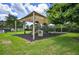 Community playground with a canopy shade, slides, climbing structures, and safety ground cover at 2527 Butterfly Landing Dr, Land O Lakes, FL 34638