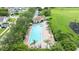 Aerial view of a long rectangular pool with lounge chairs, palm trees, and a clubhouse at 2527 Butterfly Landing Dr, Land O Lakes, FL 34638