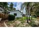 View of the backyard and exterior of home, surrounded by mature trees and partial privacy fence at 2609 Sunnyside Cir, Palm Harbor, FL 34684