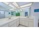 Bright bathroom features dual sinks, a large mirror, and light tile flooring for a modern look at 2609 Sunnyside Cir, Palm Harbor, FL 34684