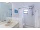 Cozy bathroom with a white sink, shower with curtain, and decorative beach themed sign on the wall at 2609 Sunnyside Cir, Palm Harbor, FL 34684